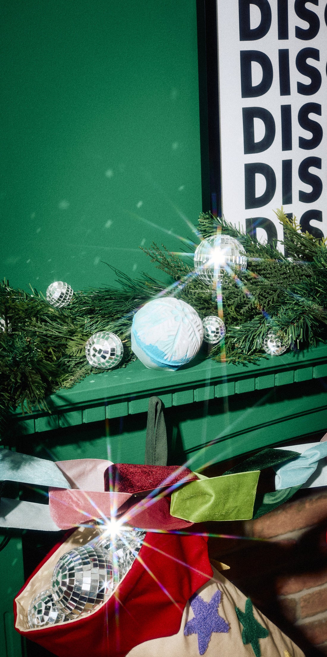 Snow Drift pale blue bath bomb resting among evergreen branches on a green mantelpiece.