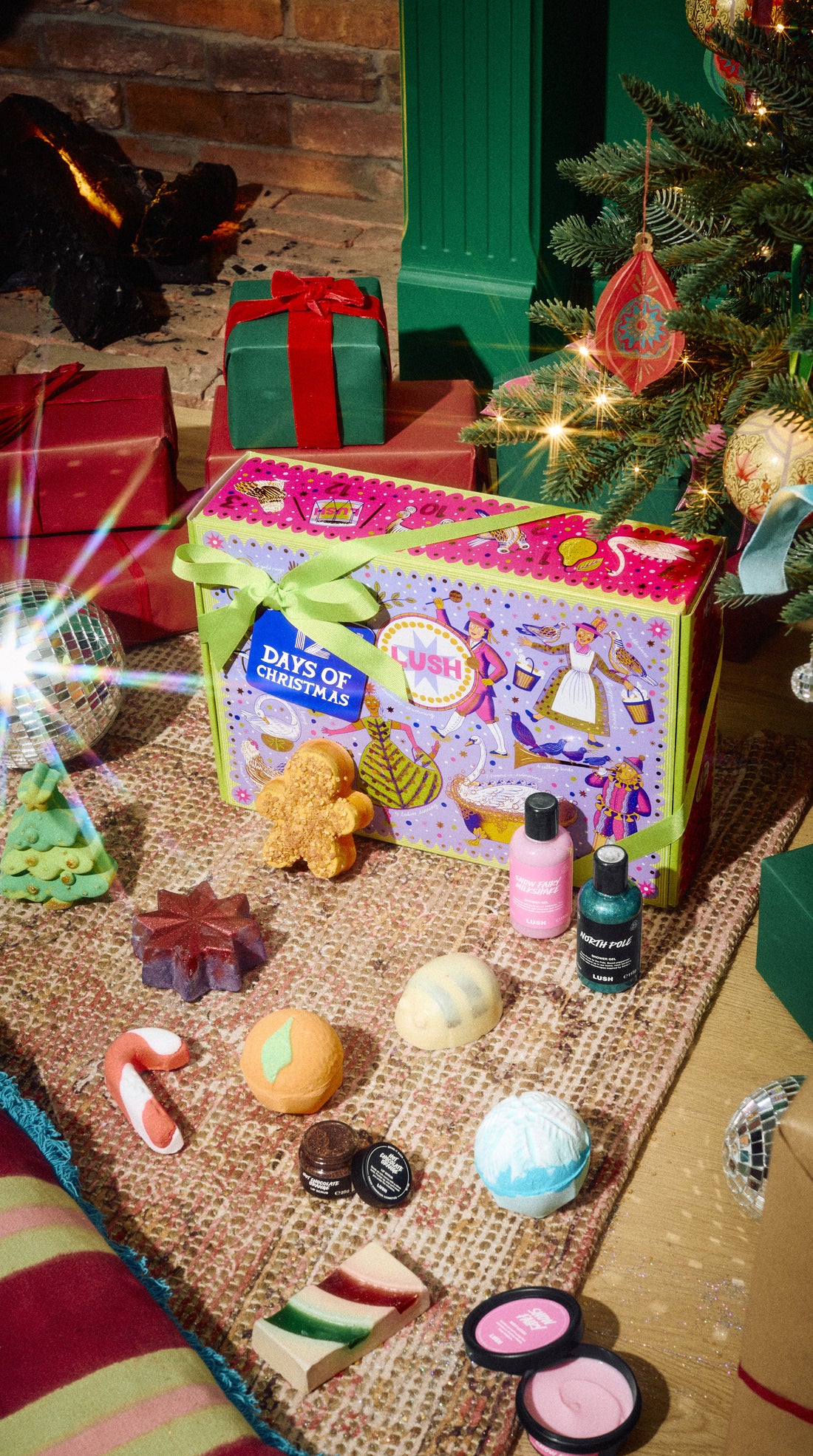 12 Days of Christmas gift box displayed with its colourful bath and body products beside a Christmas tree.