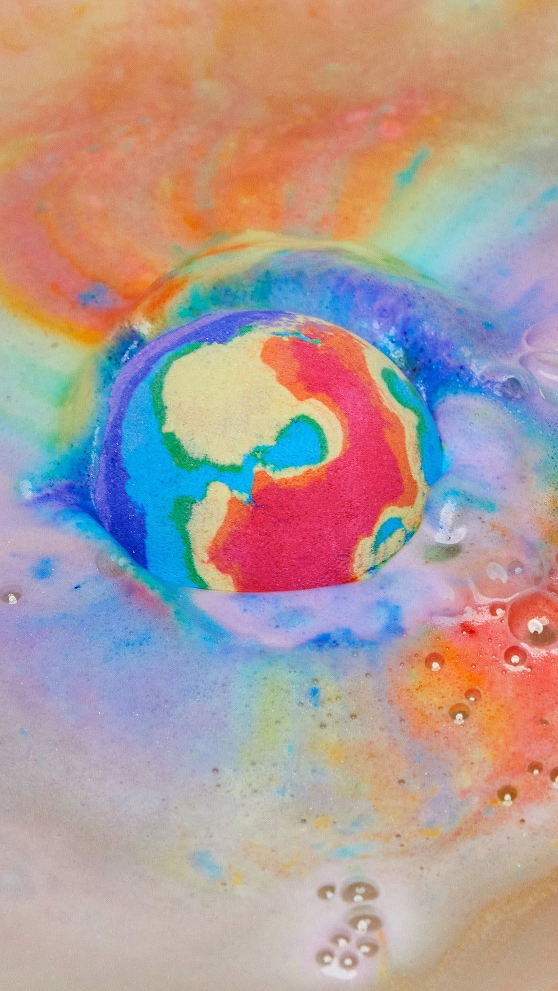The thermal Waves bath bomb is dissolving leaving behind a thick, velvety blanket of bright rainbow swirls across the surface of the water.