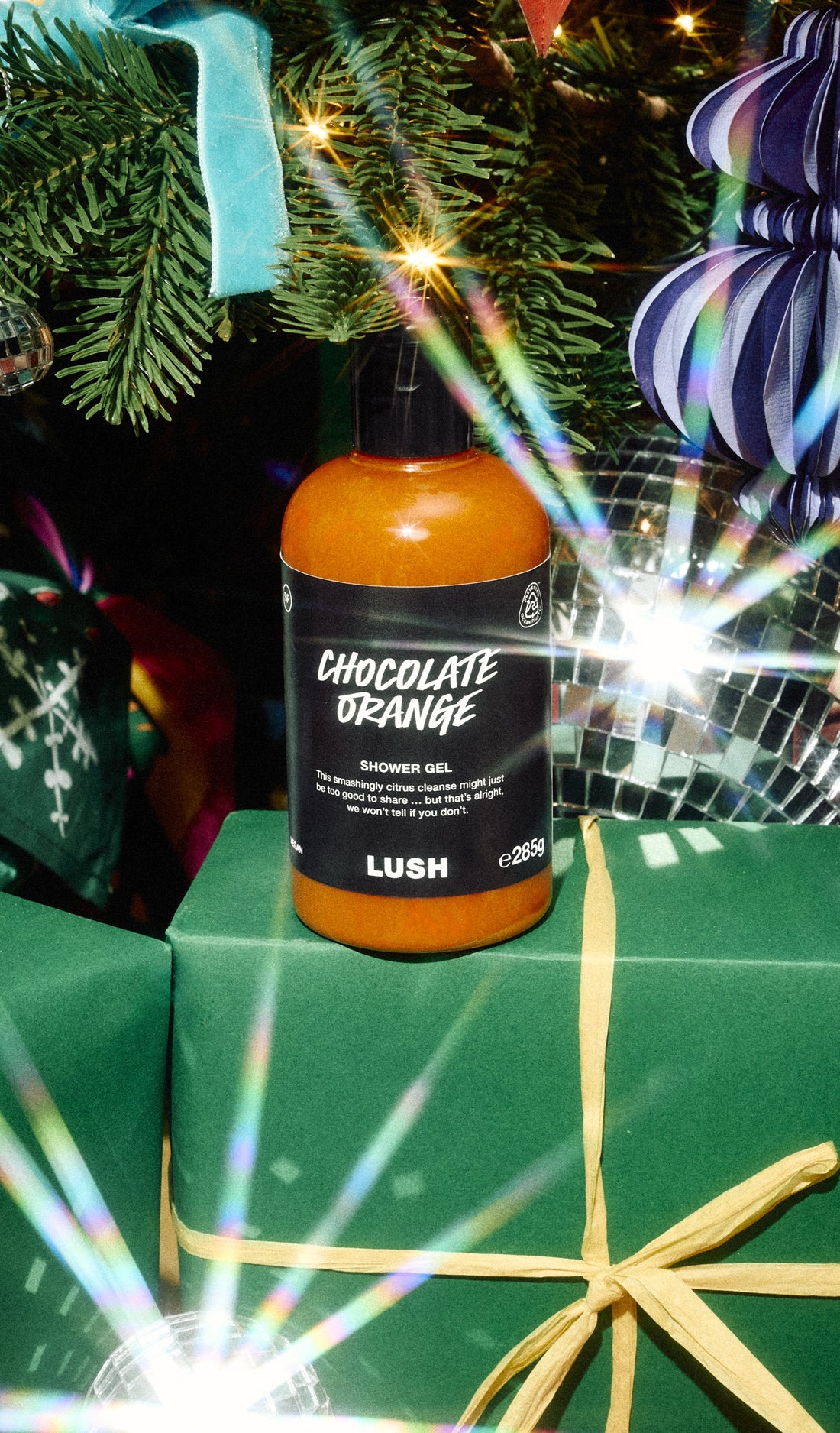 Chocolate Orange shower gel bottle standing on a green present beneath a decorated Christmas tree.