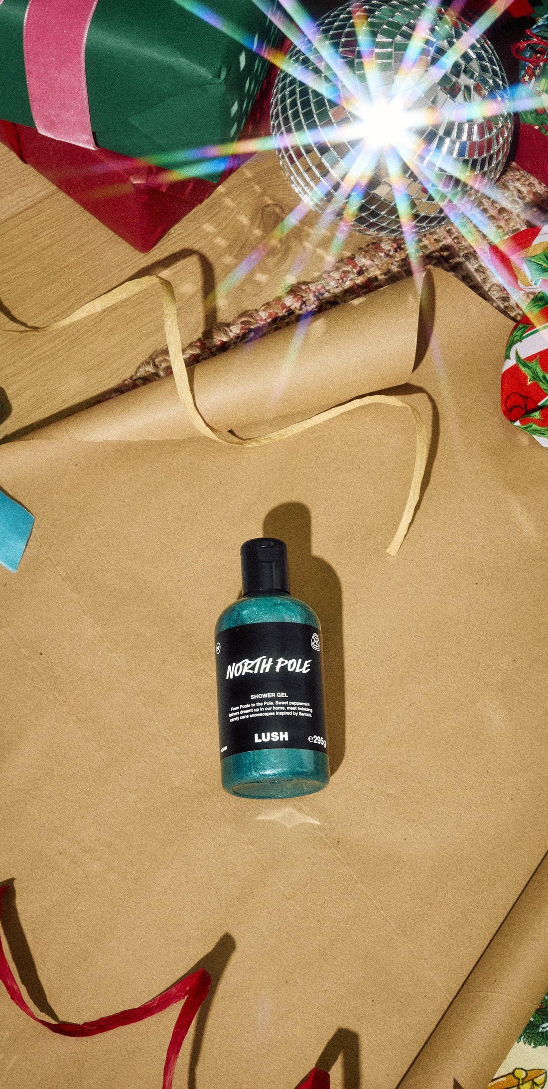 North Pole shower gel bottle on gold wrapping paper among Christmas presents and ribbons.