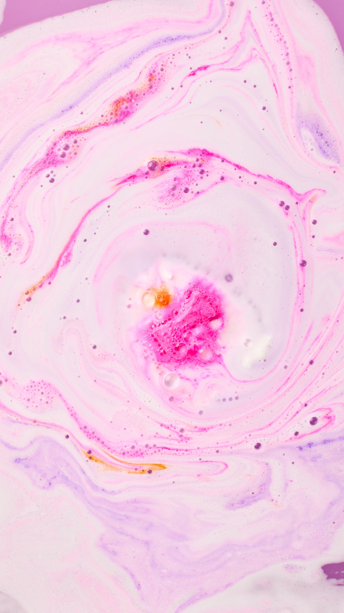 Pink and purple foam swirling as The Christmas Penguin bath bomb dissolves.