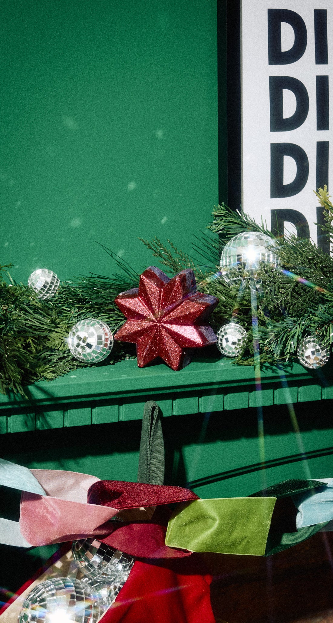 Red star-shaped Ruby Comet bubble bar on a green mantelpiece among Christmas baubles and greenery.