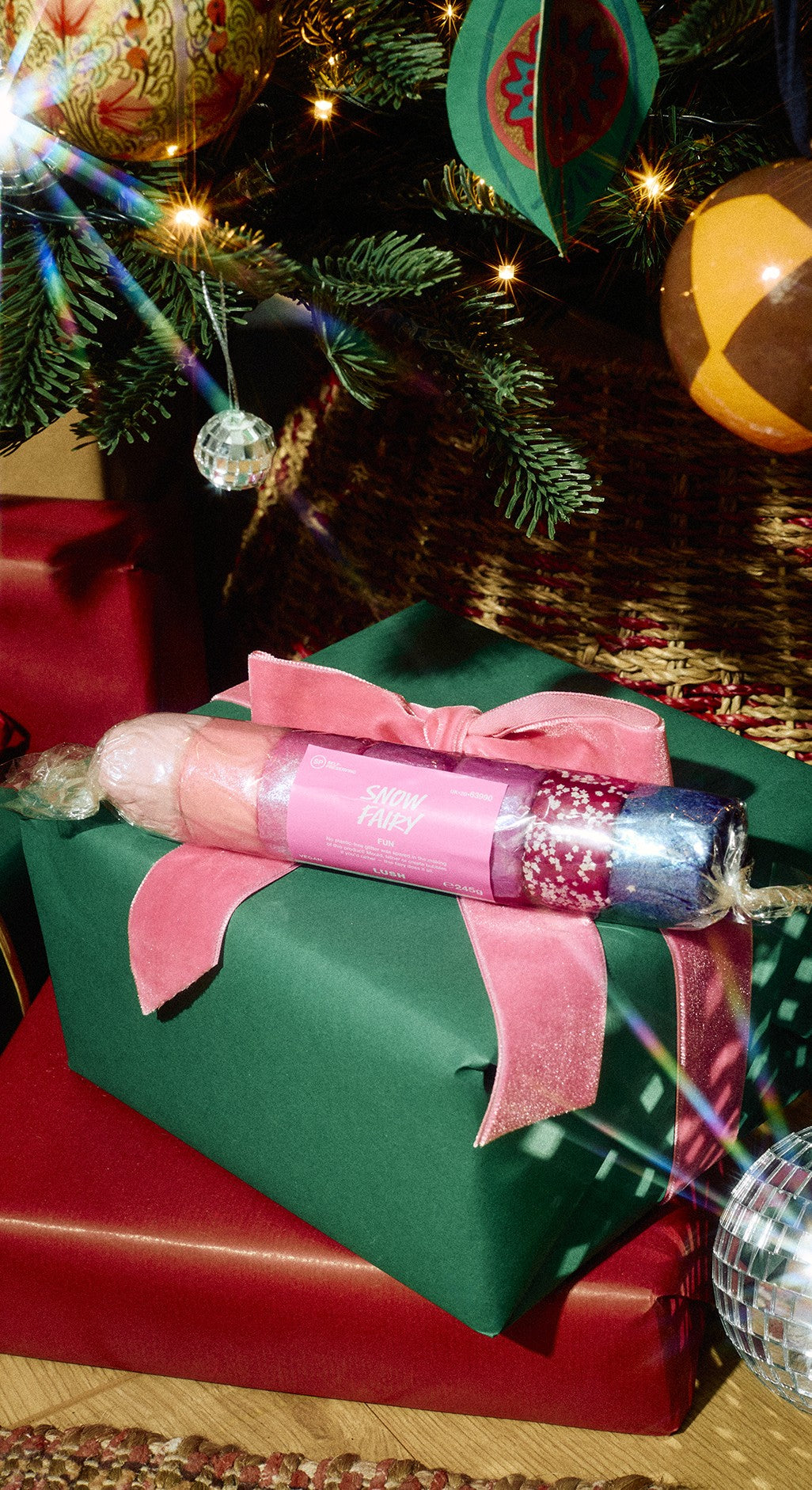 A wrapped roll of Snow Fairy Fun rests on a green gift box tied with a pink ribbon.