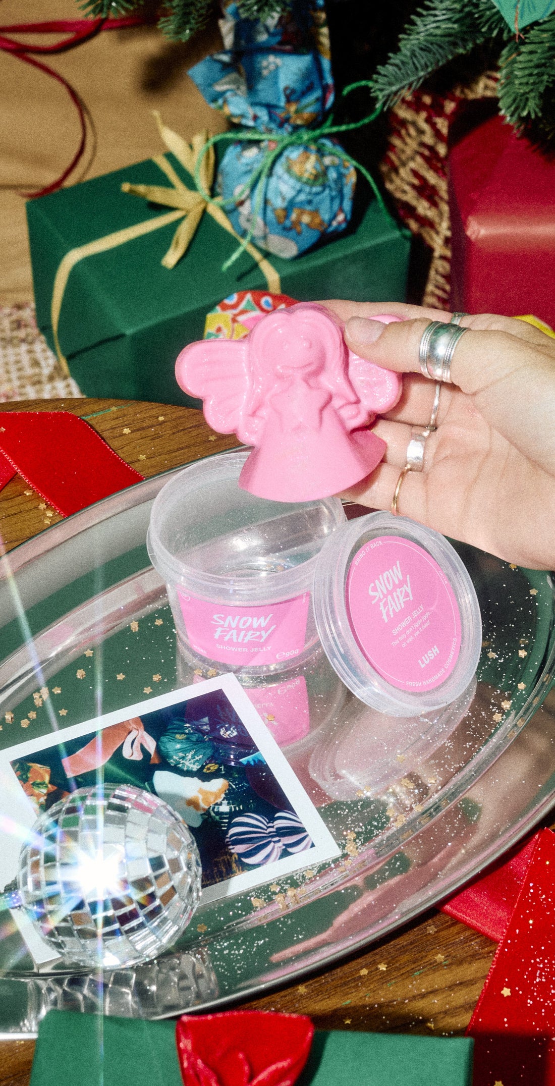 A hand lifts a pink fairy-shaped Snow Fairy shower jelly above its open pot on a festive silver tray.