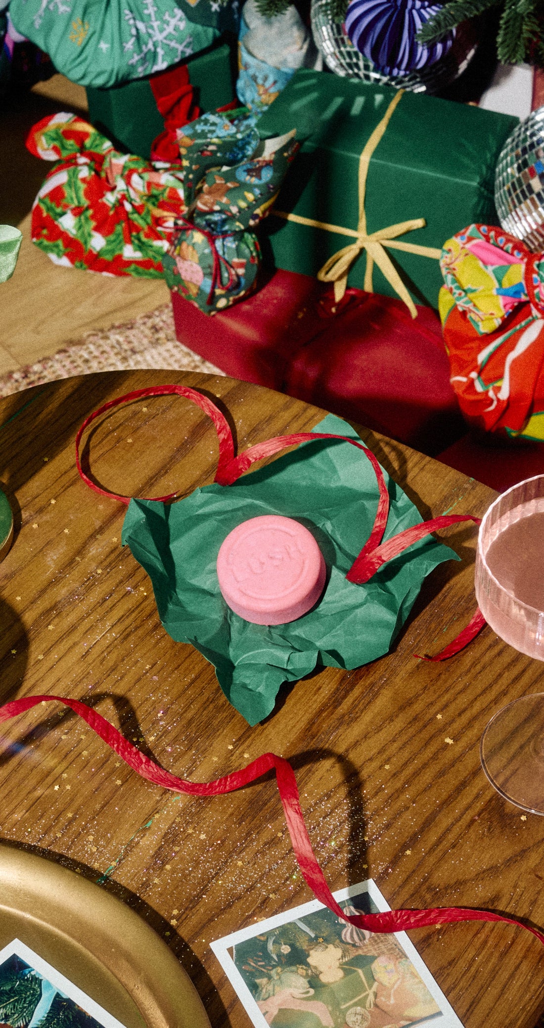 A pink Snow Fairy shampoo bar on green wrapping paper beside an open round tin and Christmas gifts.