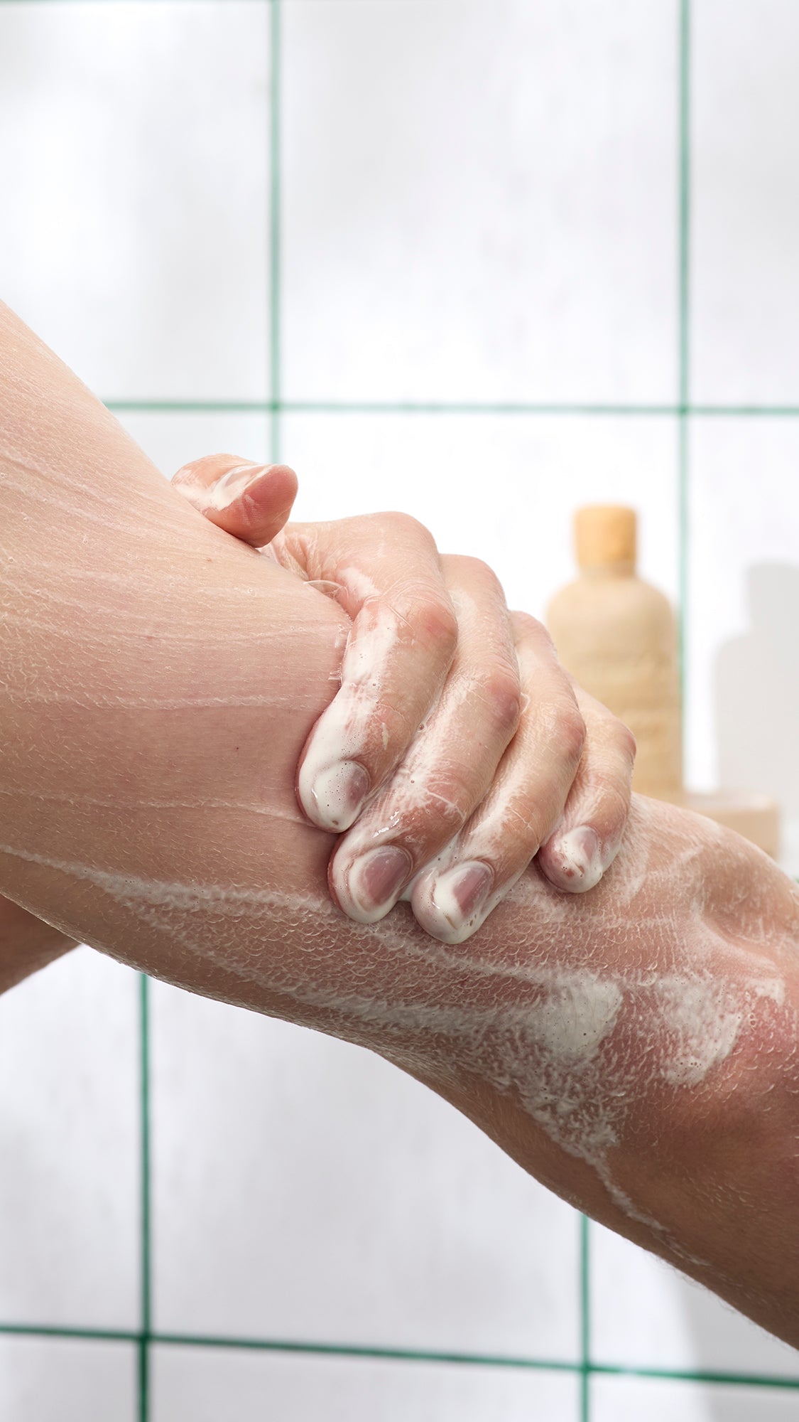 Close-up of a hand washing a forearm with Sticky Dates shower-gel lather.