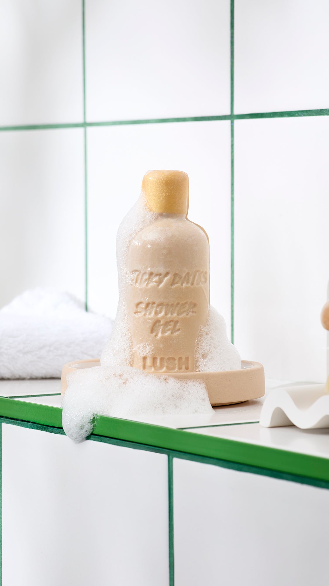 Bottle-shaped Sticky Dates naked shower gel stands on a soap dish with white lather around its base.
