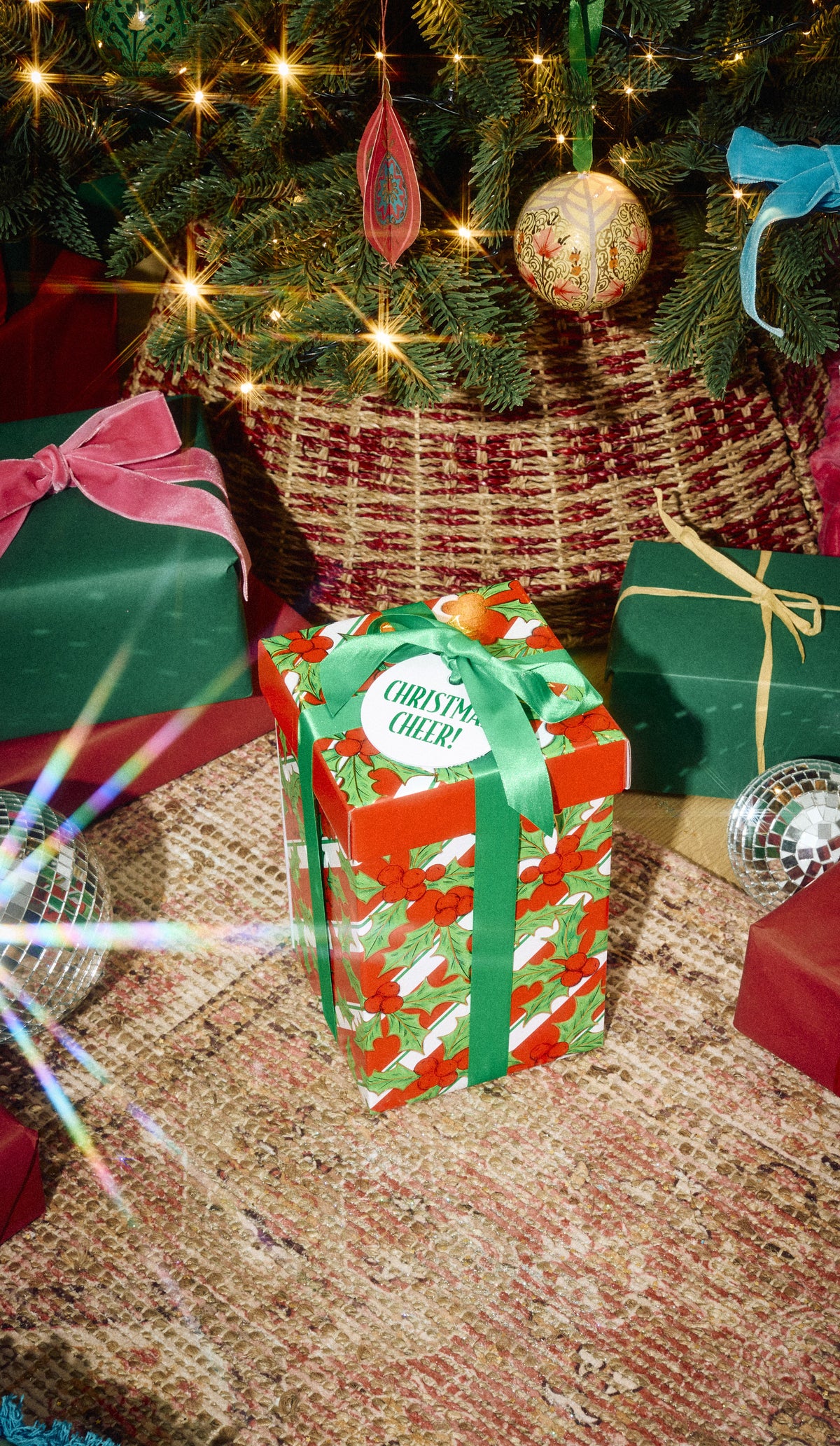 Christmas Cheer! gift in patterned green wrapping beneath a decorated Christmas tree.