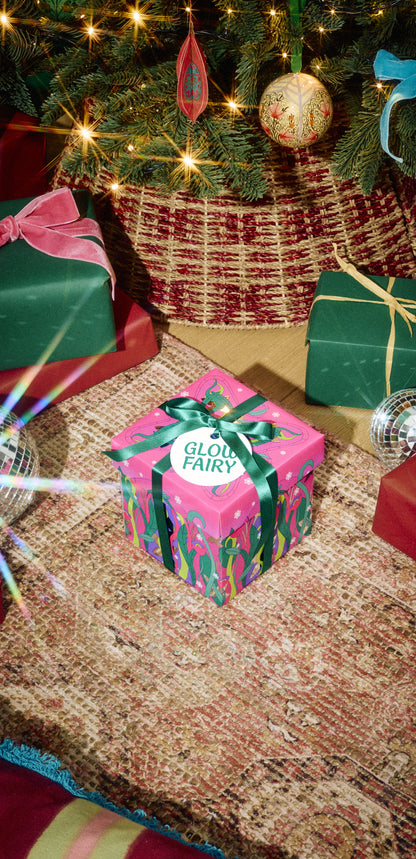 Glow Fairy gift in pink-and-green wrapping with a green ribbon beside Christmas presents.