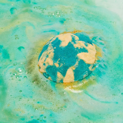 The Druid of Bath bath bomb is slowly dissolving leaving behind bubbly swirls of deep green and golden yellow foam.