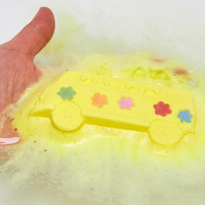 The Magic Bus bath bomb is sat in the bath water, still intact, giving off a thick velvety blanket of canary-yellow foam.