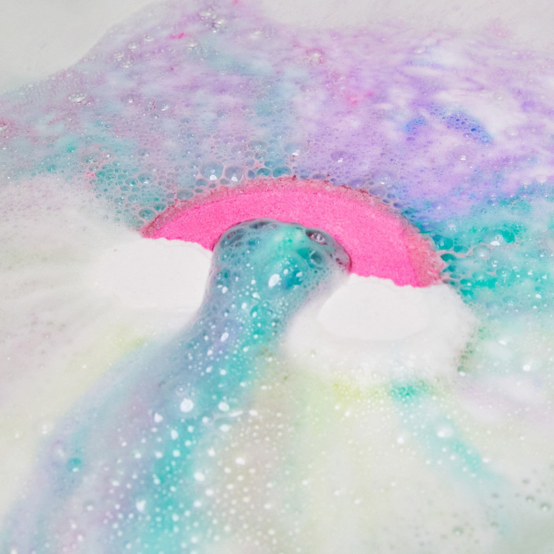 The Somewhere bath bomb is slowly dissolving leaving behind delicate, pink and blue pastel waters with thin velvety foam.