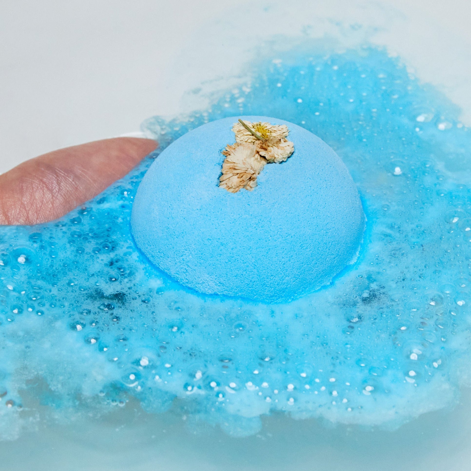 The One With Chamomile bath bomb has completely dissolved leaving behind a sea of deep blue swirls and a handful of dried chamomile flowers floating on top of the water. 