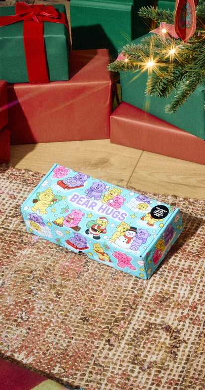 Bear Hugs gift box with colourful bear illustrations on a rug beside Christmas presents.