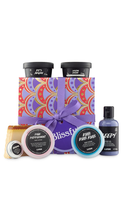 Blissful Gift featuring a variety of shower and body care products displayed around a purple, red and gold graphic patterned hat box. 