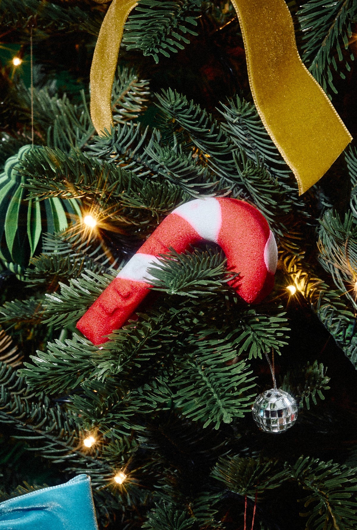 Candy Cane red-and-white bubble bar nestled among branches of a decorated Christmas tree.