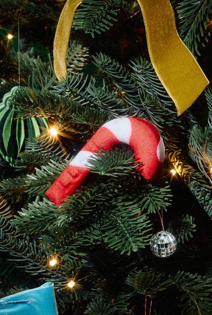 Candy Cane red-and-white bubble bar nestled among branches of a decorated Christmas tree.