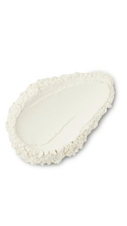 A cream coloured tear-shape swatch of a lush dusting powder. 