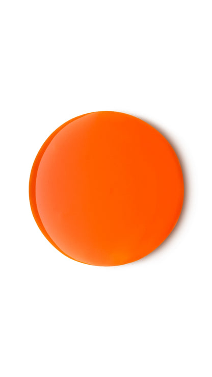 An orange circular translucent swatch of a lush shower gel. 