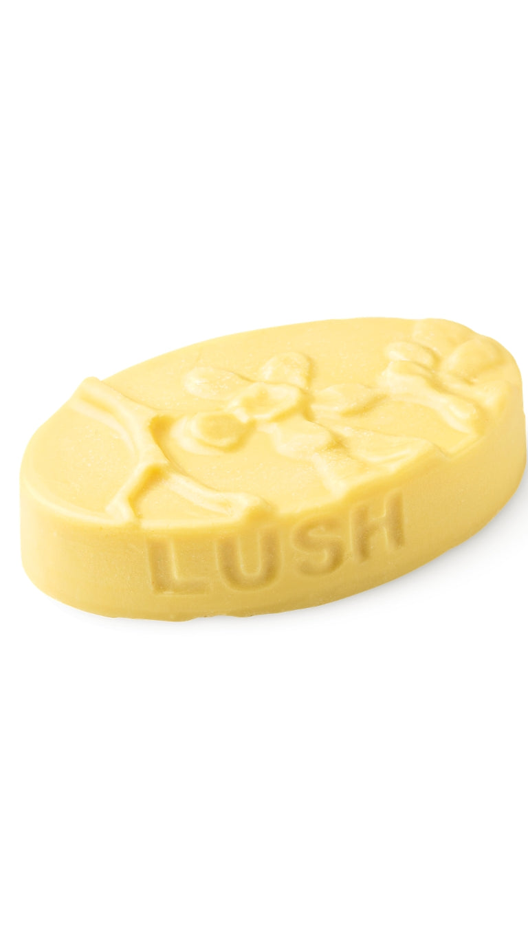 A yellow oval-shaped lush massage bar that smells like citrus. 