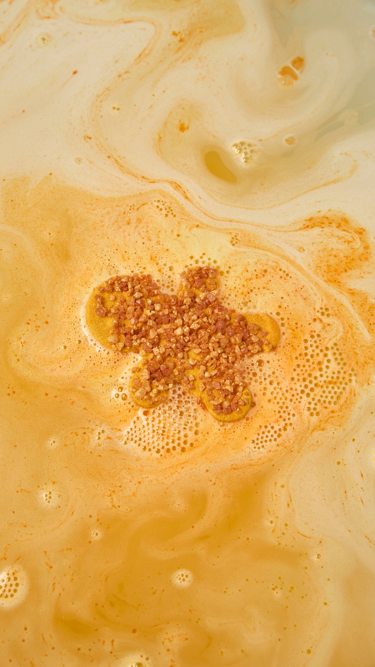 Gingerbread-shaped bath bomb surrounded by swirls of orange and cream foam.
