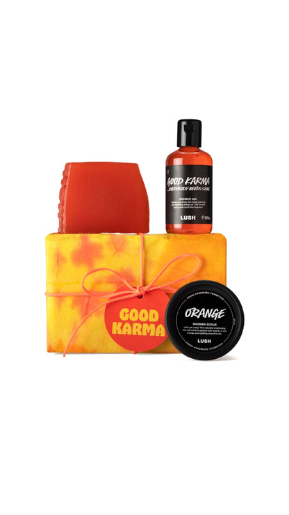 Good Karma Gift featuring Karma soap piece, Orange body scrub and Good Karma, Everybody Needs Some shower gel displayed around a vibrant tie-dyed wrapped gift box. 