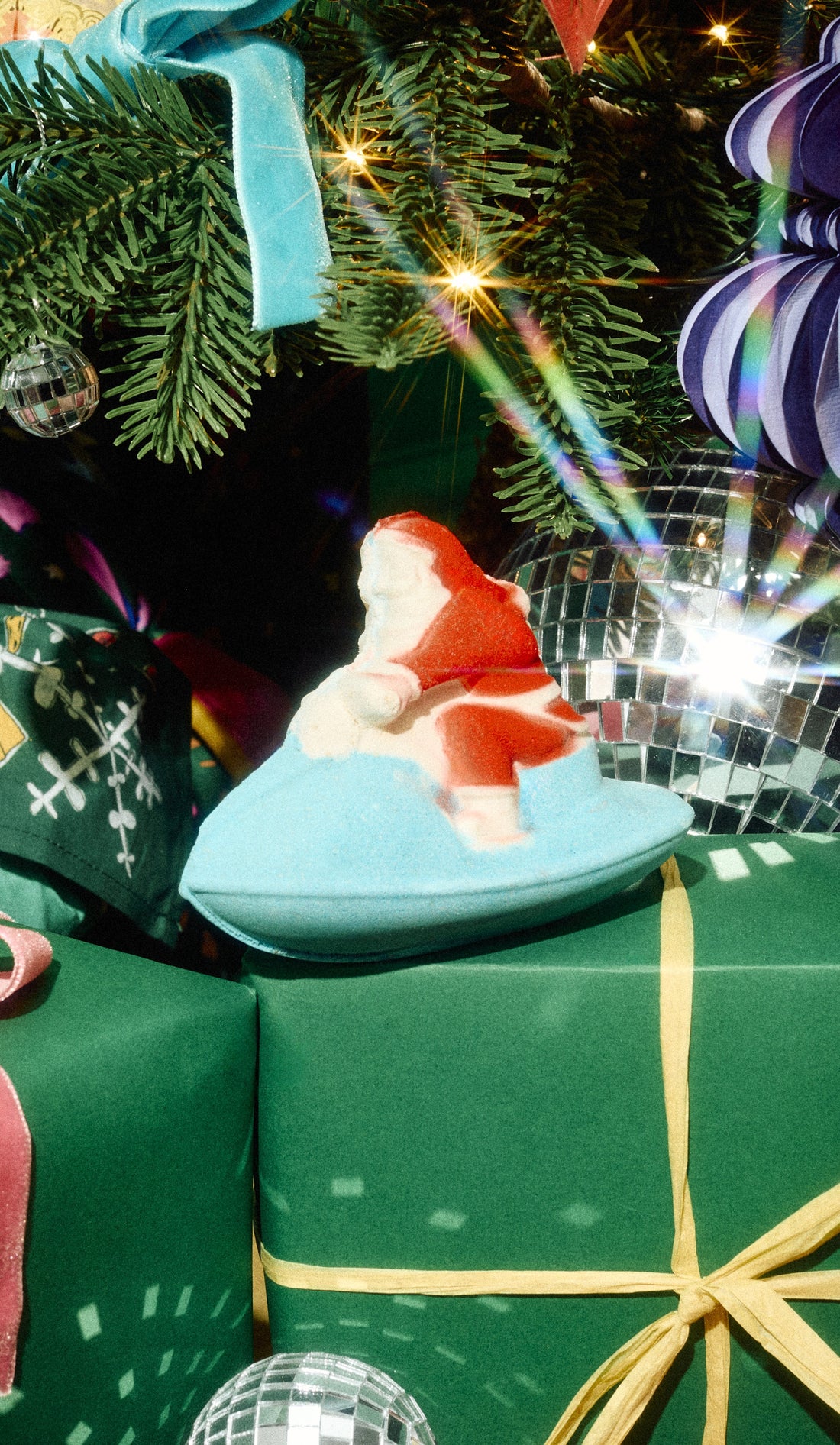 Santa-shaped Jet Ski bath bomb on a turquoise jet ski among green Christmas presents.