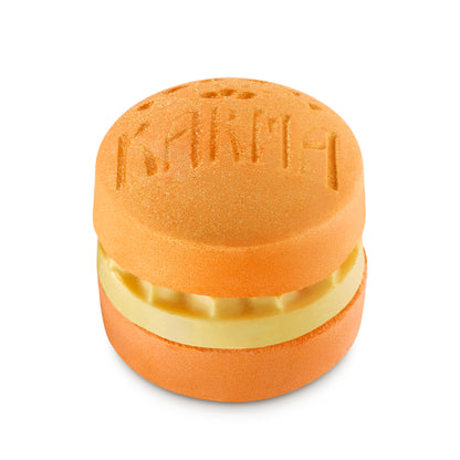 Orange macaron-shaped bath bomb with a nourishing bath oil layer in the center.