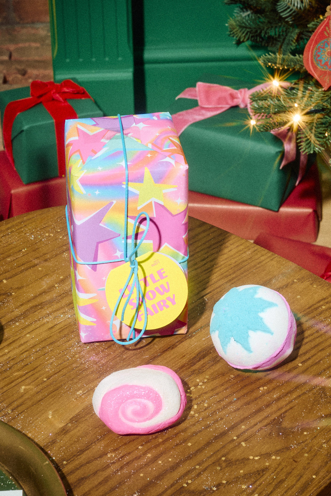 Little Snow Fairy gift wrapping beside a pink spiral bubble bar and a blue-and-pink bath bomb with a white star.