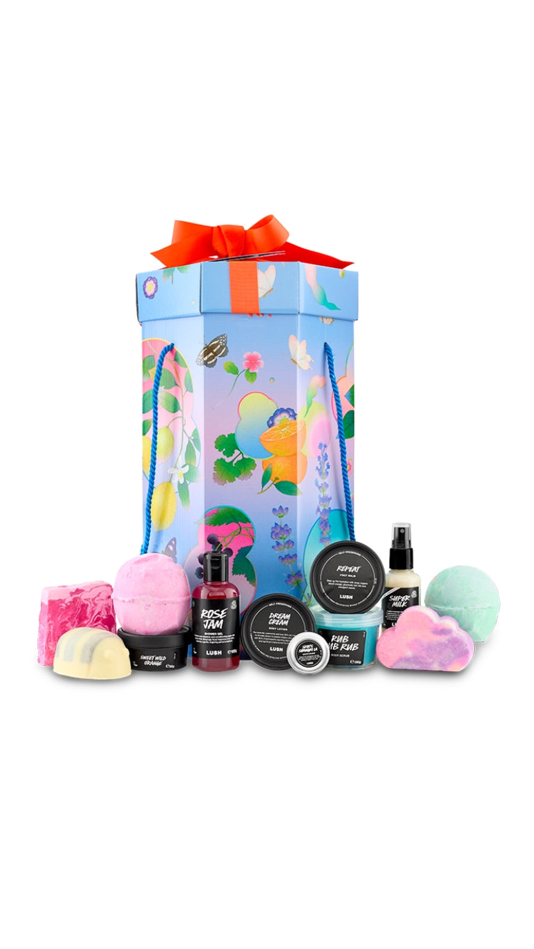 Lush Life gift featuring a selection of bath bombs, bubble bars, body care products and shower essentials displayed around a decorative gift box.