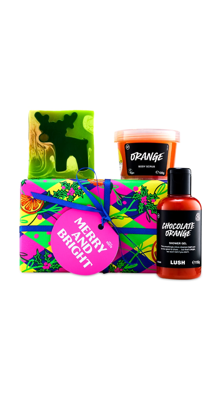Merry and Bright gift featuring the most famous reindeer of all soap piece, orange body scrub, and chocolate orange shower gel, displayed around a graphic wrapped gift box.