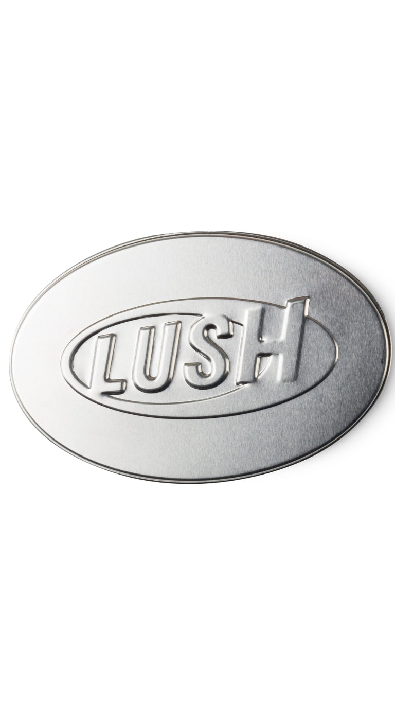 A silver oval-shaped tin with LUSH imprinted on the lid. 