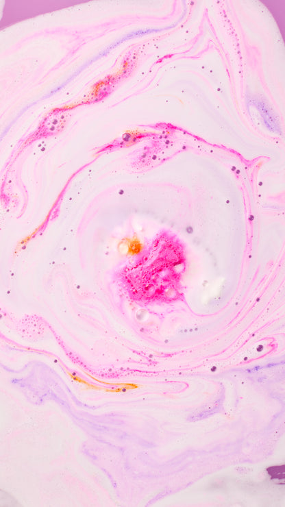Pink and purple foam swirling as The Christmas Penguin bath bomb dissolves.