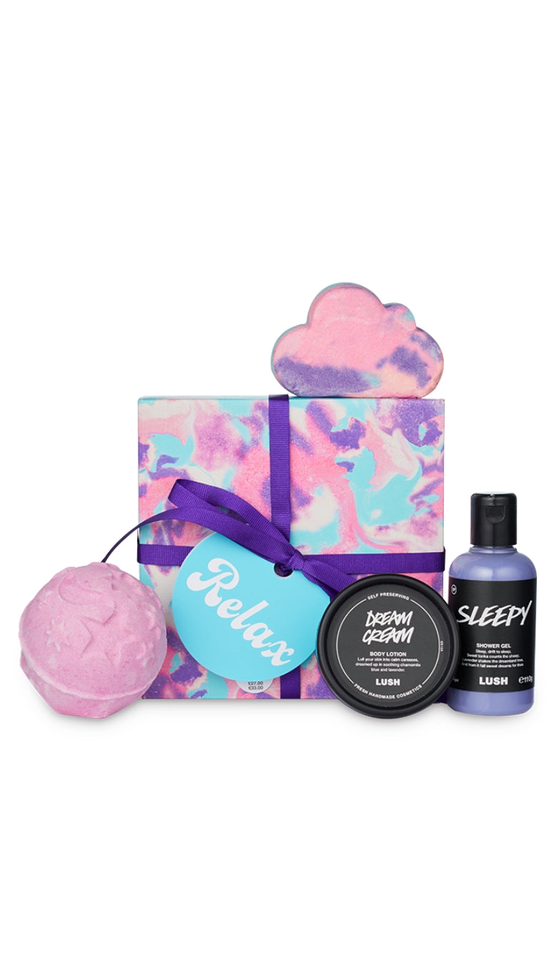 Relax Gift featuring Sleepy shower gel and bubble bar, Twilight bath bomb, and Dream Cream body lotion displayed around a square colourful marbled hat box gift. 