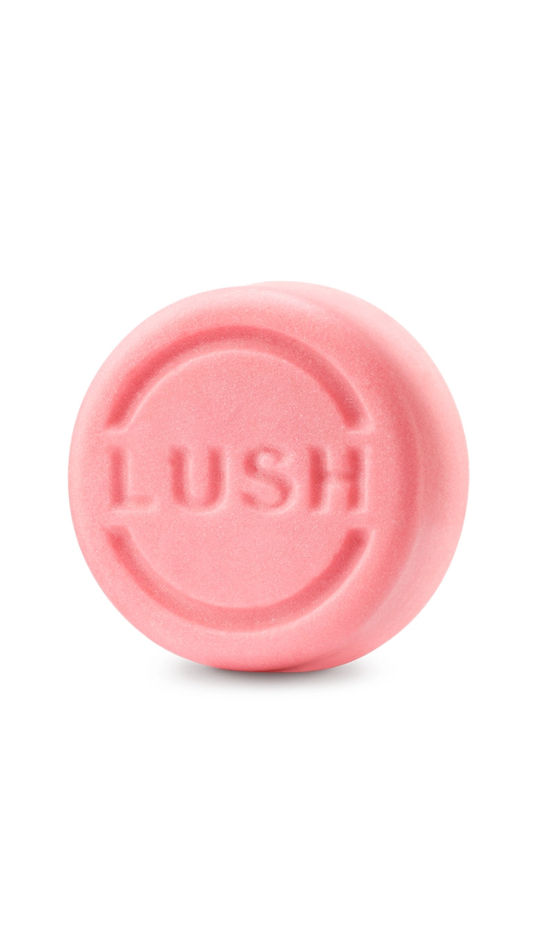 A pink circular lush shampoo truckle bar. 