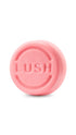 A pink circular lush shampoo truckle bar. 