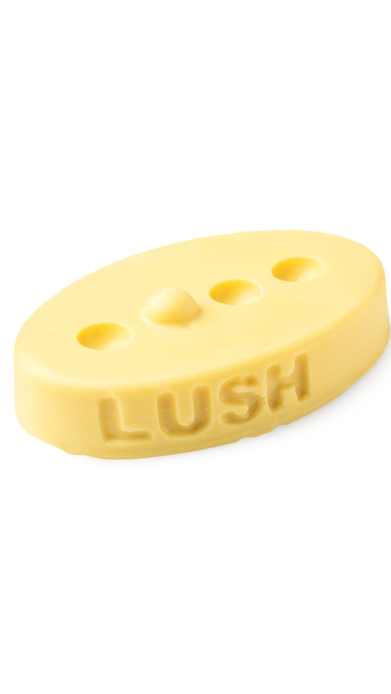 A yellow oval-shaped lush massage bar that smells like citrus.