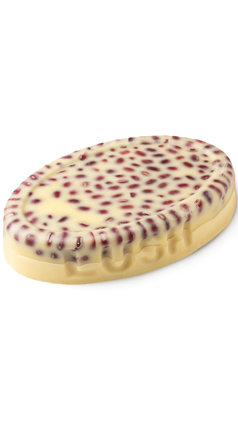 A cream oval-shaped lush massage bar with berries on the top 