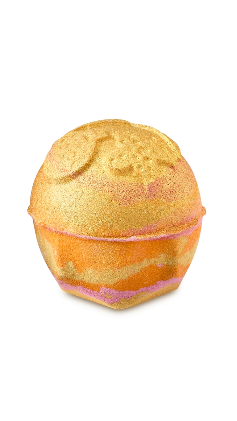 An orange and cream circular shaped bath bomb with ornaments imprinted on the top. 