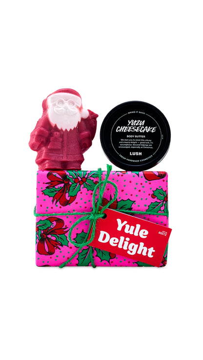 Yule Delight gift featuring festive body products displayed on top of a wrapped gift box. 