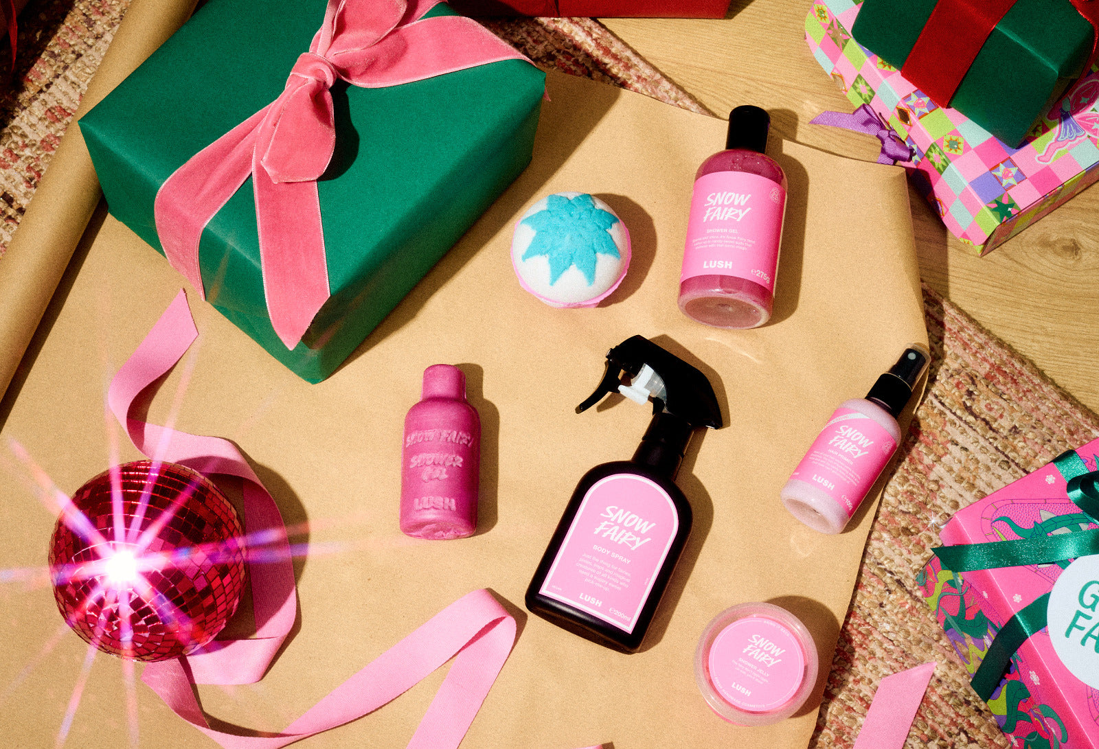 Snow Fairy bath and body products surrounded by colourful Christmas gifts and pink ribbon.